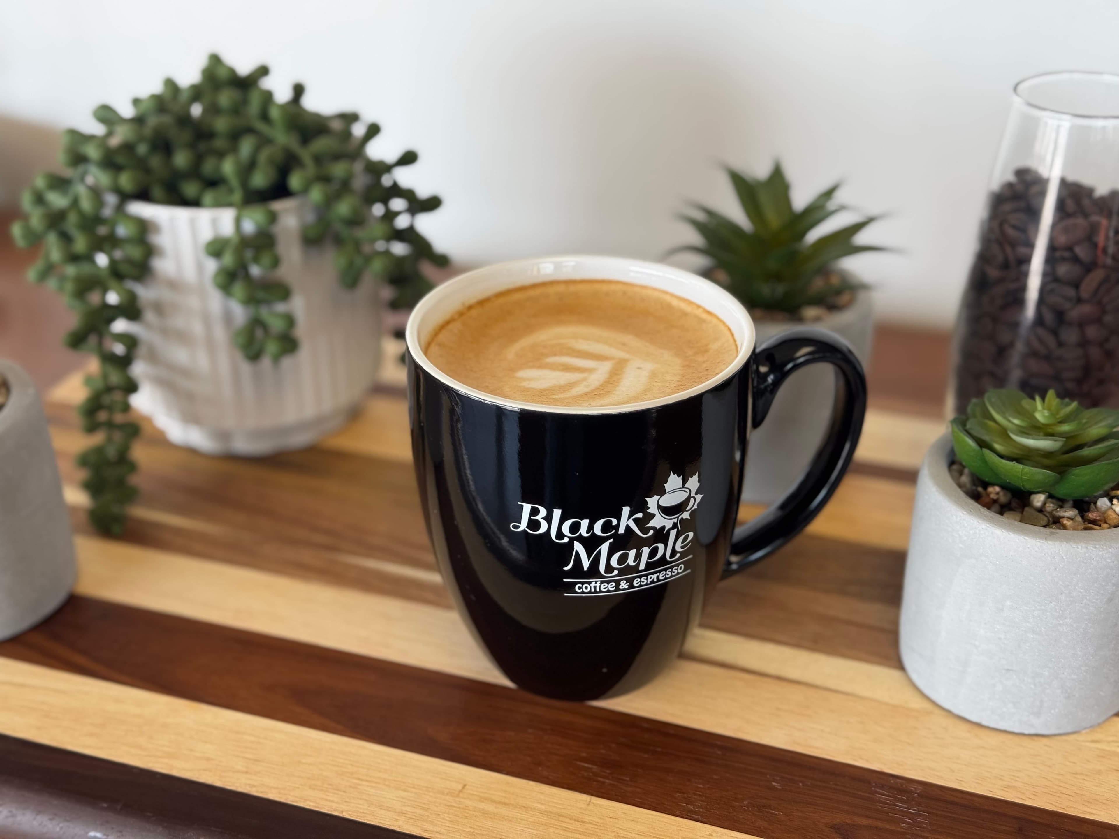 Black Maple Coffee latte in a branded mug